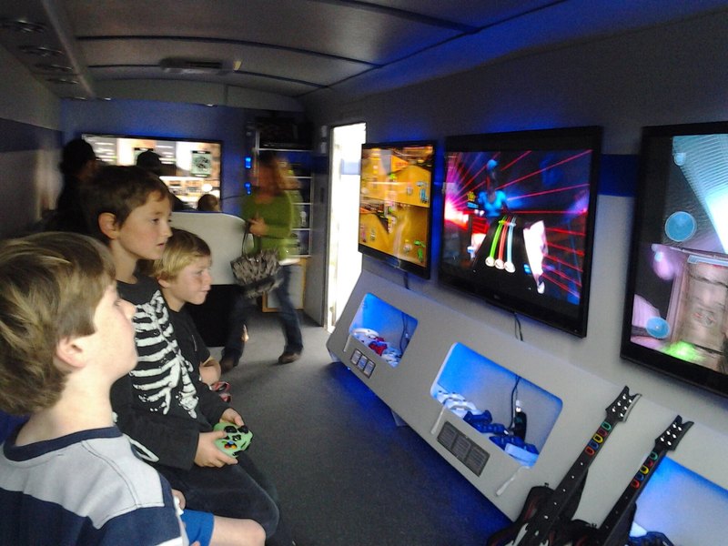 Children gathered around big screens in the bright kids play zone